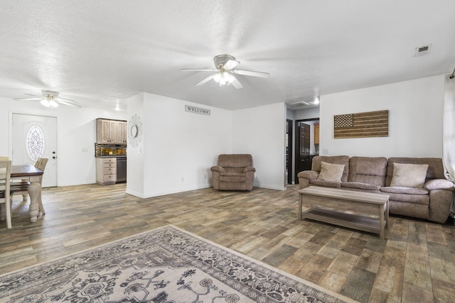 living room featuring a textured ceiling, dark hardwood / wood-style floors, and ceiling fan