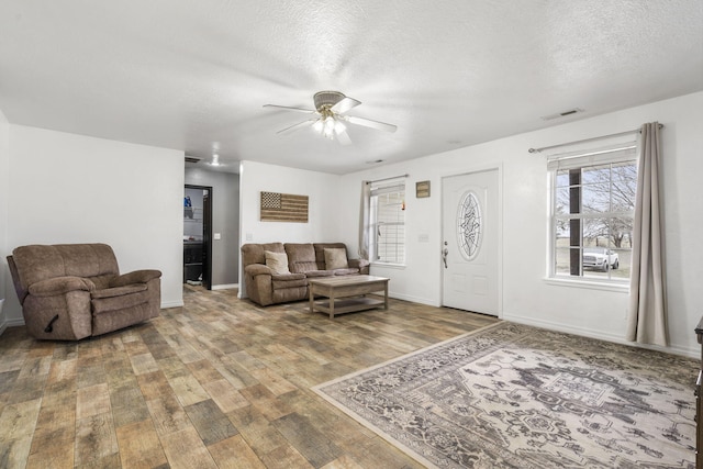 living room featuring ceiling fan, hardwood / wood-style floors, and a textured ceiling