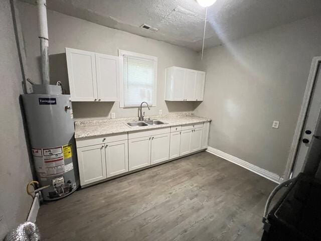 kitchen with white cabinetry, dark wood-type flooring, sink, and gas water heater