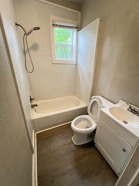 full bathroom featuring hardwood / wood-style flooring, shower / tub combination, vanity, and toilet