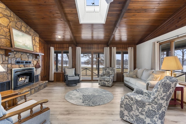 living room featuring wood-type flooring, a wealth of natural light, vaulted ceiling with skylight, and a fireplace