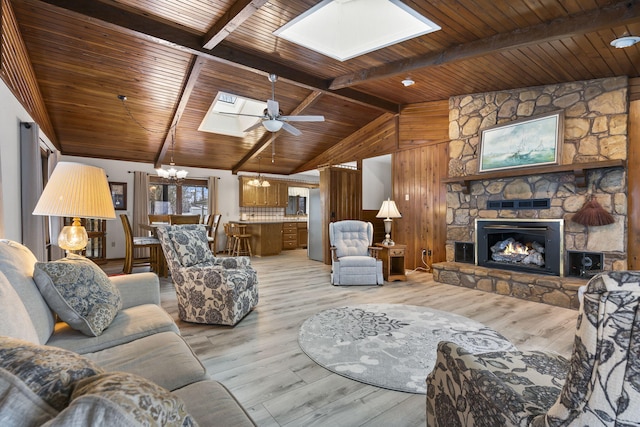 living room featuring wood ceiling, a stone fireplace, light hardwood / wood-style flooring, and vaulted ceiling with skylight