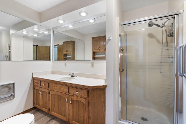 bathroom with hardwood / wood-style flooring, vanity, toilet, and walk in shower