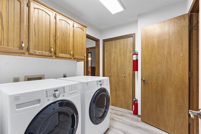 washroom featuring independent washer and dryer, cabinets, and light hardwood / wood-style flooring