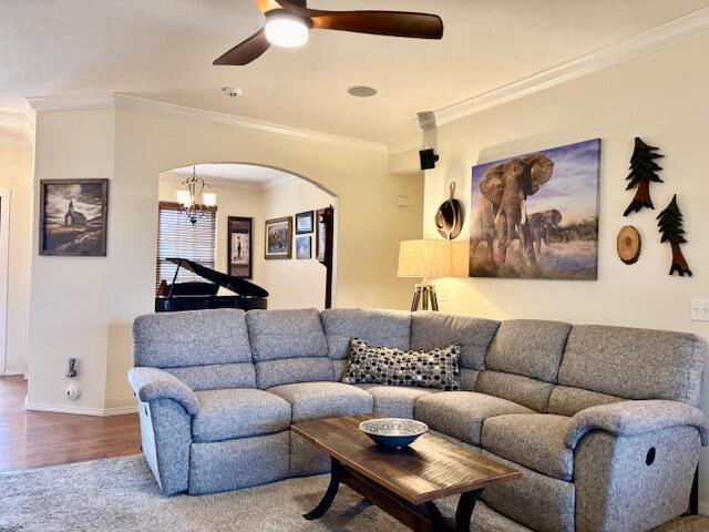 living room featuring hardwood / wood-style flooring, ceiling fan, and ornamental molding