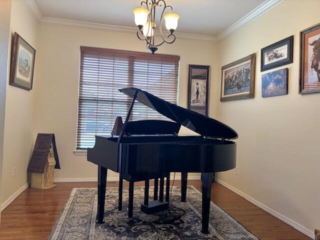 misc room with crown molding, dark hardwood / wood-style flooring, and a chandelier