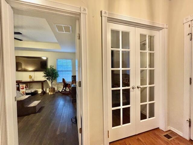 hall with french doors, a tray ceiling, and hardwood / wood-style floors