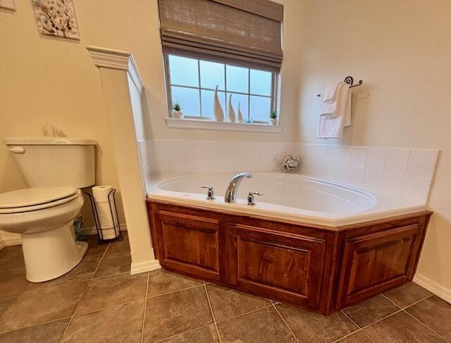 bathroom featuring a washtub, tile patterned floors, and toilet