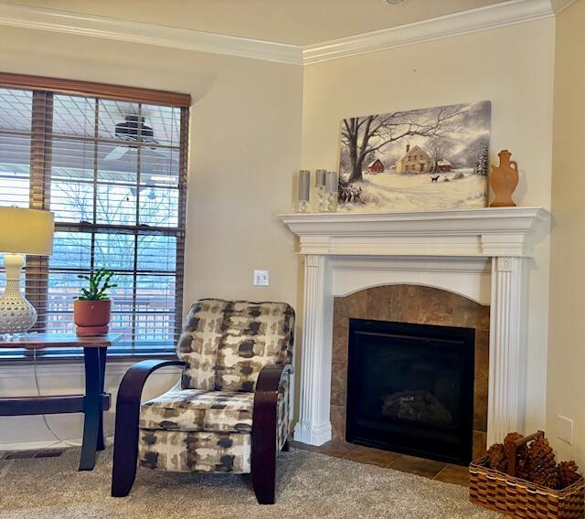 sitting room featuring a tiled fireplace, crown molding, and carpet