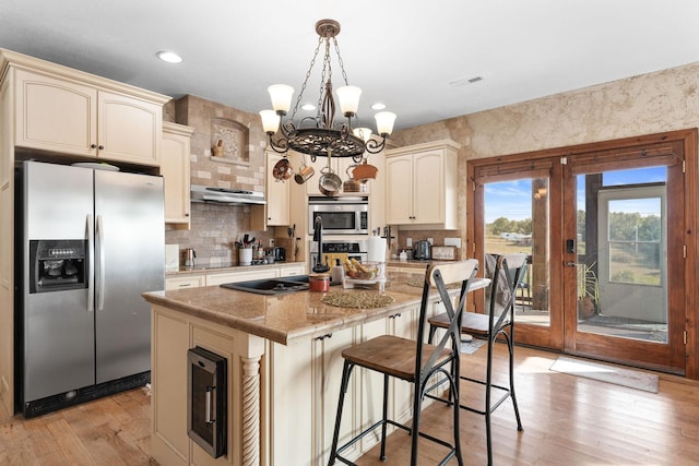 kitchen with light stone counters, cream cabinets, stainless steel appliances, and a kitchen island