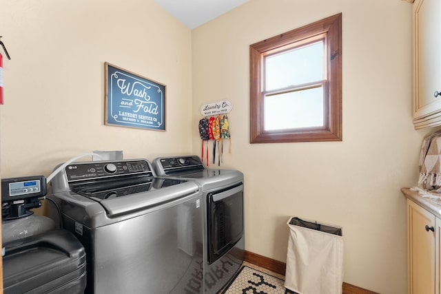 clothes washing area featuring cabinets and washing machine and clothes dryer