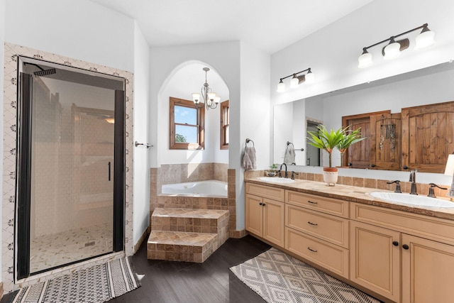 bathroom with wood-type flooring, separate shower and tub, vanity, and a chandelier