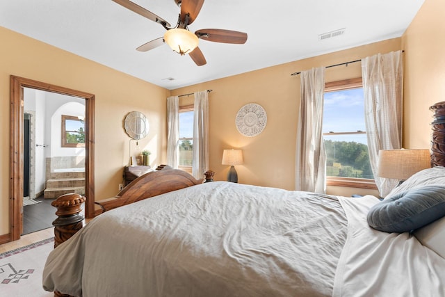 bedroom featuring ceiling fan, connected bathroom, and multiple windows