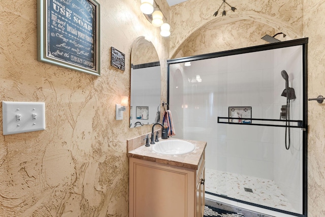 bathroom with a tile shower and vanity