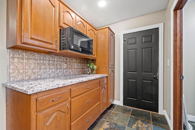 kitchen featuring tasteful backsplash and light stone counters