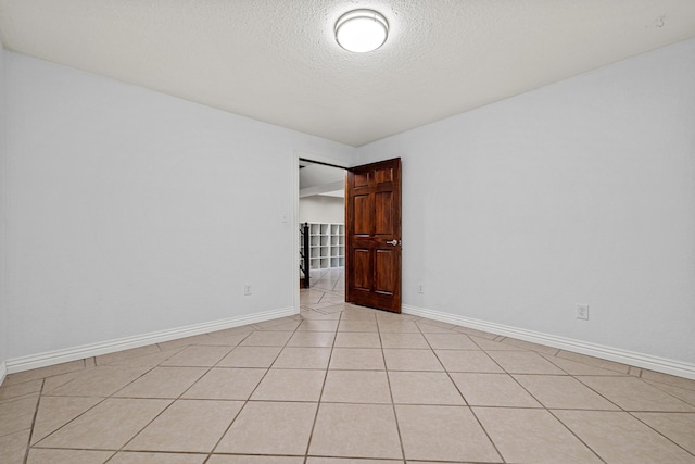 empty room with a textured ceiling and light tile patterned floors