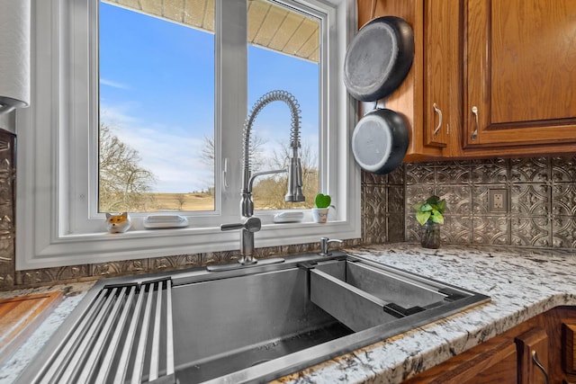 room details with light stone countertops, sink, and decorative backsplash