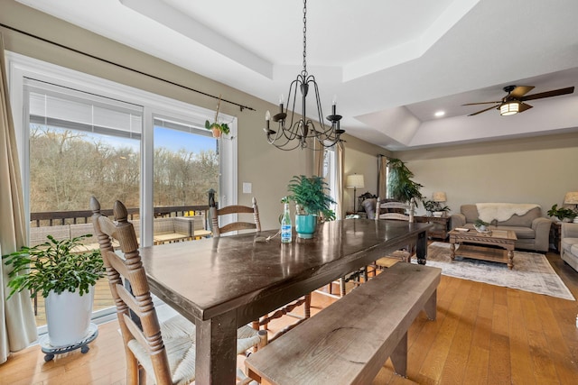 dining area with ceiling fan, a tray ceiling, and light hardwood / wood-style flooring