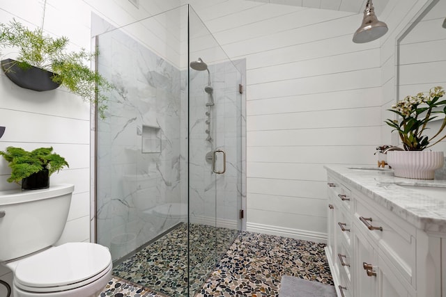 bathroom with wooden walls, vanity, toilet, and an enclosed shower