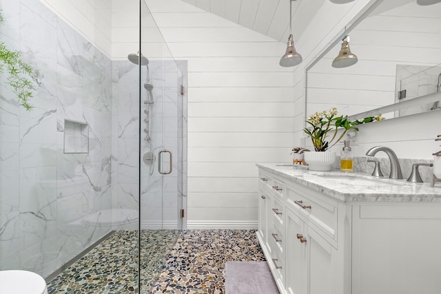 bathroom featuring a shower with door, vanity, lofted ceiling, and wood walls