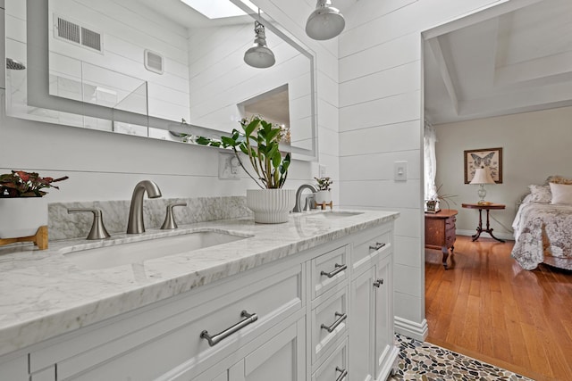 kitchen featuring white cabinetry, sink, light stone counters, and a skylight