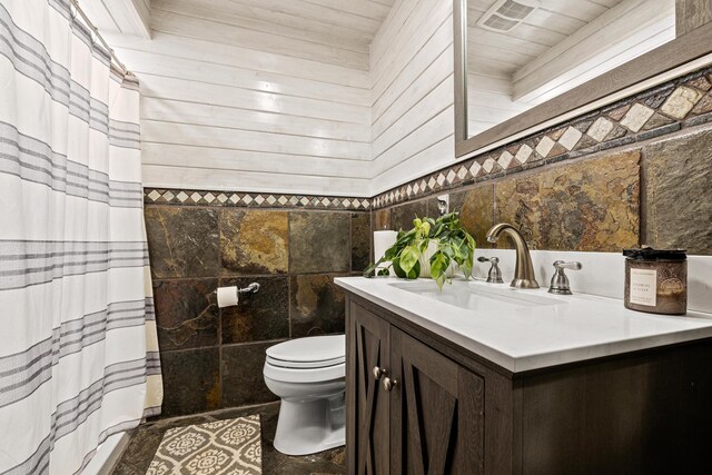 bathroom with vanity, tile walls, and toilet