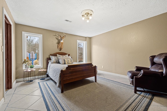 tiled bedroom featuring multiple windows and a textured ceiling