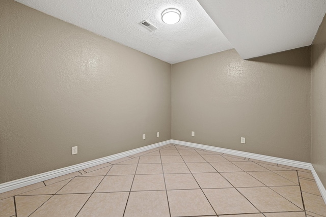 tiled empty room featuring a textured ceiling