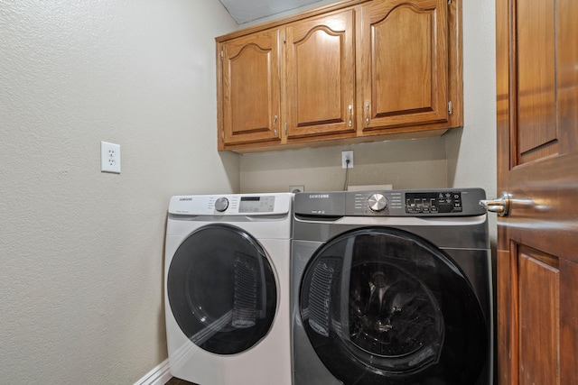 laundry area with washer and clothes dryer and cabinets