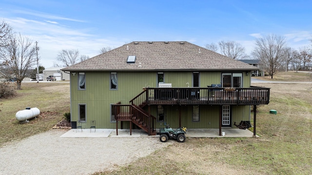 rear view of property with a wooden deck, a lawn, and a patio