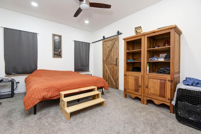 carpeted bedroom featuring ceiling fan and a barn door