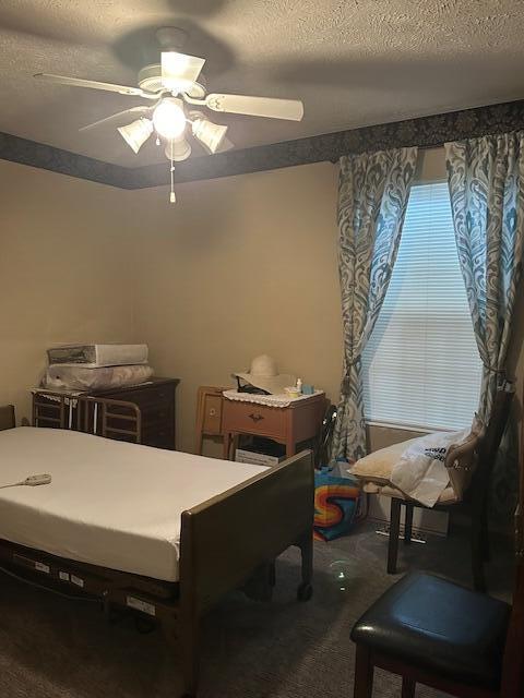 bedroom featuring ceiling fan, dark carpet, and a textured ceiling