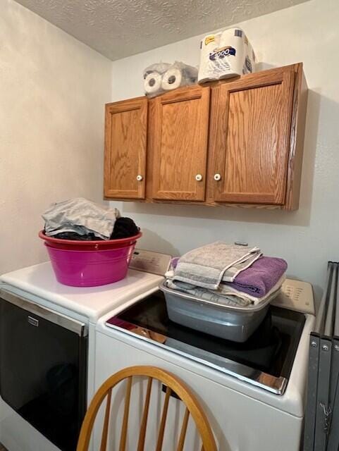 laundry room featuring cabinets, washer and dryer, and a textured ceiling