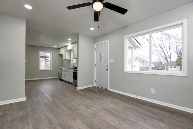 unfurnished living room featuring hardwood / wood-style flooring, ceiling fan, and sink