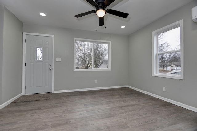 foyer entrance with hardwood / wood-style flooring, an AC wall unit, a wealth of natural light, and ceiling fan