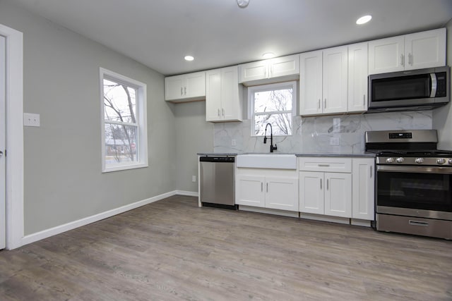 kitchen featuring stainless steel appliances, sink, white cabinets, and backsplash