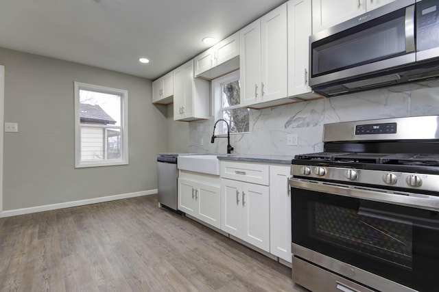 kitchen featuring white cabinetry, appliances with stainless steel finishes, light stone countertops, and decorative backsplash