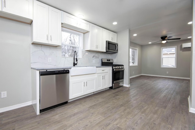 kitchen with white cabinetry, sink, stainless steel appliances, and a wall mounted AC