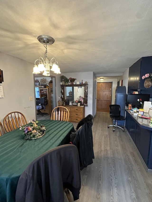 dining space with hardwood / wood-style floors, a textured ceiling, and a notable chandelier