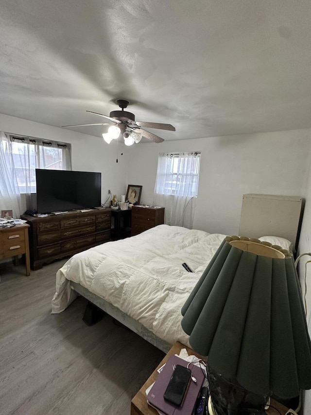 bedroom with hardwood / wood-style flooring, ceiling fan, and multiple windows