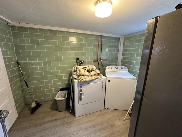 laundry area with independent washer and dryer and light hardwood / wood-style flooring