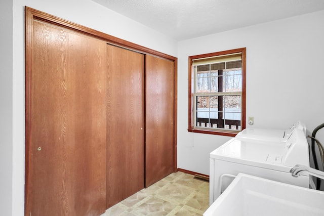 laundry room with sink, washer and clothes dryer, and a textured ceiling