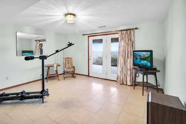 exercise area featuring light tile patterned floors and a textured ceiling