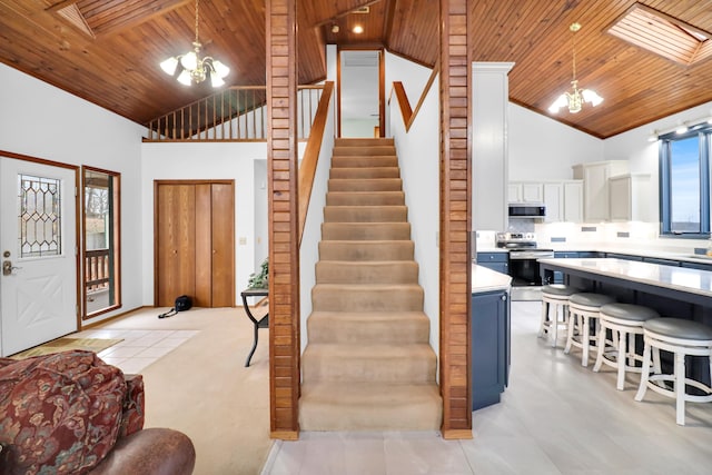 staircase with an inviting chandelier, wood ceiling, and high vaulted ceiling