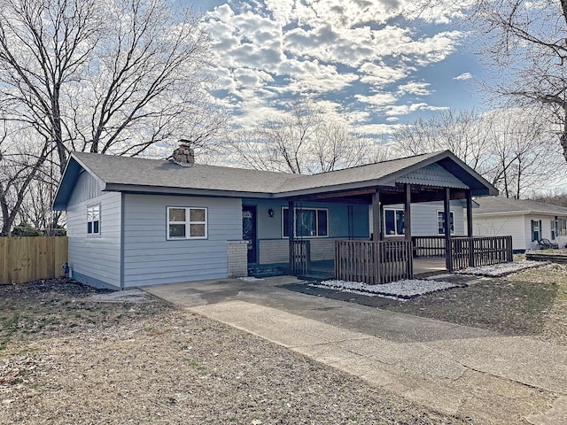 view of front facade with a porch, a chimney, and fence