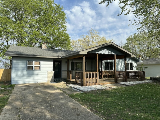 view of front of property with a chimney, a front lawn, and covered porch