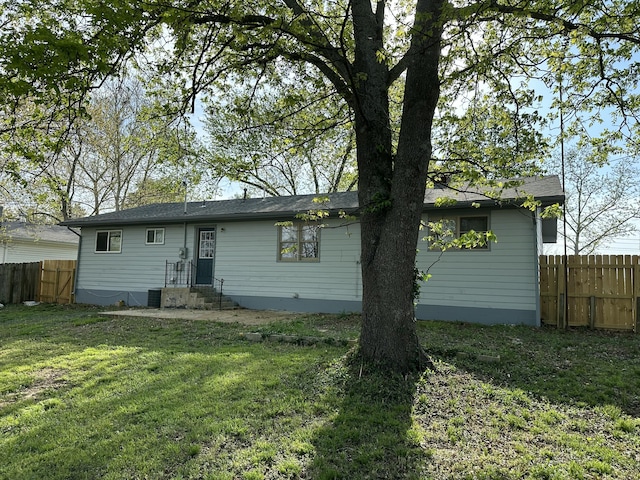 rear view of property with a yard and fence