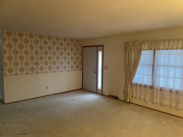 carpeted entrance foyer featuring a textured ceiling