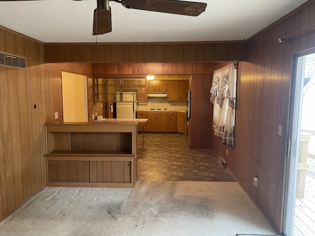 kitchen with wooden walls, oven, a textured ceiling, and white fridge