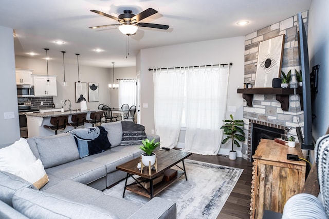 living room featuring wood-type flooring, sink, ceiling fan, and a fireplace